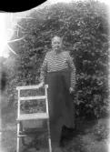 Äldre kvinna stödjer sig på en stol, 1920-tal