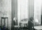 Rumsinteriör med stolar, litet bord i rokokostil, piedestal, spetsgardiner mm. troligen från Centralpalatset i Gävle stad.