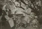 Maria stickar och moderna Tilda väntar på sitt kaffe i trädgården i Lillkyrka, omkring 1920