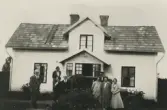 Familjen samlad runt gästernas bil som är parkerad vid Stenhammar i Lillkyrka, 1940-tal