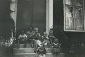Astrid sitter på trappan till missionshuset i Mäjsta i Ringkarleby tillsammans med flera barn, 1940-tal
