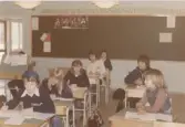 En skolklass sitter i sina bänkar i ett klassrum, Brattåsskolan 1970- till 80-tal. I bakgrunden ses 