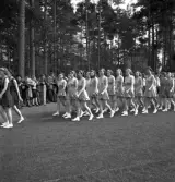 Gymnastikuppvisningen, 25/5 1941. 
Kvinnliga gymnaster tågar in på Värendsvallen. Genom skogen i 
bakgrunden skymtar några av kasernerna på I 11.