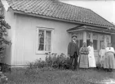 Familj framför stuga, 1920-tal