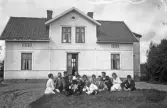 Famijegrupp fotograferad framför hus, 1920-tal