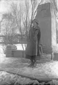 Kvinna i kappa och hatt vid minnessten, 1920-tal
