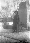 Kvinna i lång kappa och hatt vid minnessten, 1920-tal
