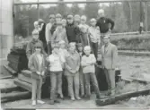 Elever från Brattåsskolan åk 6 står samlade utomhus med läraren Rolf Werner. De är på lägerskola till Ransbergs Herrgård i Värmland 1960-tal.