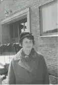 Småskollärarinna Sonja Andersson, iklädd hatt och kappa, står utanför Kålleredsskolans entré (senare Brattåsskolan) 1970-tal.