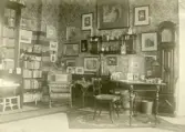 Fotot visar ett rum med bl.a , skrivbord, bokhyllor, golvur, tavlor  mm. troligen biblioteket inifrån Gysinge herrgård.