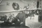Elon Bengtsson (1900 - 1984) på sin 50-årsdag, Sporred 1950. Han uppvaktas med blommor i hemmet. Son till Hilda och Bernhard Bengtsson, Sporred.