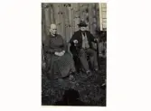 Johanna och Bengt i Syrhult. Det gamla paret sitter invid en omålad stugvägg.