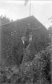 Två män vid kolonistuga med klätterväxter i Örebro, 1920-tal