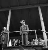 Gymnastikuppvisningen, 25/5 1941. 
En man i militäruniform talar i mikrofonen på läktaren till Värendsvallen.