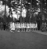 Gymnastikuppvisningen, 25/5 1941. 
Kvinnliga gymnaster tågar in på Värendsvallen, åtföljda av en
kvinnlig ledare i vit dräkt.