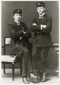 Två unga män hos fotografen, i kostym och skärmmössa med emblem.
Ernst Bjersing (senare kronolänsman och landsfiskal) till höger, under studietiden.
Helfigur, ateljéfoto.