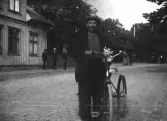 Okänd man med trehjulig cykel och en blombukett vid styret på Torggatan intill kv Sadelmakaren.