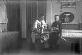 Kvinna och barn vid symaskin i köket, 1920-tal