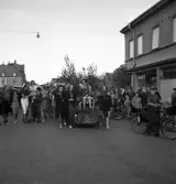 Studenterna, 3/6 1941. En kvinnlig student körs på lövad kärra fram utmed Storgatan (vid P.N. Perssons hörna). I bakgrunden ser man bl a dåv. Riksbankens hus vid Stortorget.