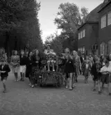 Studenterna, 3/6 1941. En kvinnlig student körs på lövad kärra utmed Västergatan, i korsningen Nygatan, norrut. Till vänster syns allén vid Teatertorget. Till höger skymtar dåv. Badhuset.