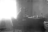 Kvinna skiver brev vid sitt skrivbord, 1920-tal