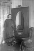 Kvinna med pälskantad klänning vid skåp, 1920-tal
