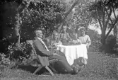 Familj vid ett dukat kaffebord i trädgården, 1920-tal