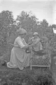 Kvinna med litet barn i korgstol med skinnfäll, 1920-tal