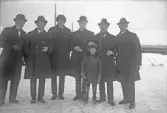 Sex män och en pojke poserar på isen framför kameran, 1920-tal