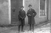Två män i överrock och hatt utanför Edvard Svensson kontor, 1920-tal