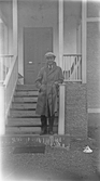 Ung man i överrock och keps på trappa, 1920-tal