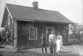 Familjegrupp framför torp, 1920-tal