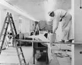 Reparations- och målningsarbeten. Till vänster fönster åt Mäster
Samuelsgatan.