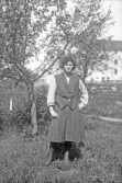 Kvinna i kjol och väst ute i trädgården, 1920-tal