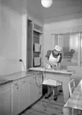 En kvinna står i ett kök och stryker, Uppsala 1938