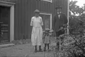Ungt par med litet barn framför hus på landet, 1920-tal