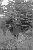 Man i överrock och hatt röker cigarr i skogsglänta, 1920-tal
