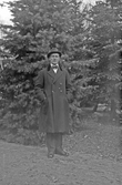 Man i överrock och hatt i skogsglänta, 1920-tal