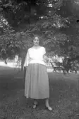 Kvinna står framför en gran i parken, 1920-tal