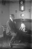 Man i kostym vänder sig mot hunden i soffan, 1920-tal