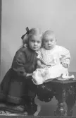 Barnporträtt. Syskonen Karin och Karl-Gustav Lagerblad. Karin med rosett i håret och babyn Karl-Gustav sittande på ett bord. Karin gifte sig 1932 med dåvarande museichefen Albert Sandklef.