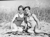 Två unga kvinnor (ej identifierade) solbadar på en strand, sannolikt Apelviken. Noterat på negativfack 