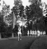Svenska Flaggans dag 1943. 
Ett antal kvinnliga gymnaster i vita gymnastikdräkter, tågar in
på Värendsvallen.