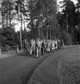 Svenska Flaggans dag 1943. 
En manskör i sångarmössor och kostym m.m., tågar in på
Värendsvallen, under ledning av körledaren Bertil Rask.