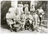 Korpral Axel Spång (blivande fjärdingsman), i dörröppningen tillsammans med kockar och kökshandräckning på Kronobergshed, ca 1890.
