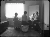 Gruppporträtt. Man och kvinna sitter framför spegel i ett sovrum, K. E. V..
Ur Gustaf Åhmans samling.