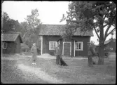 Exteriör, byggnader, tre personer och en hund.
Ur Gustaf Åhmans samling.