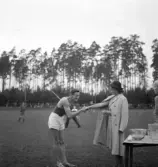 Internationellt på Värendsvallen, 1943. 
Prisutdelning. 
En man från Ungern tar emot ett pris från en ung dam i kappa och hatt.