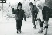 Fotografi på tre barn, två flickor och en pojke, åkandes skridskor, 1969.