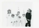 Fotografi på ett luciatåg med lucia, tärna, stjärngossar och tomte, Monika och Sven Karlssons barn.